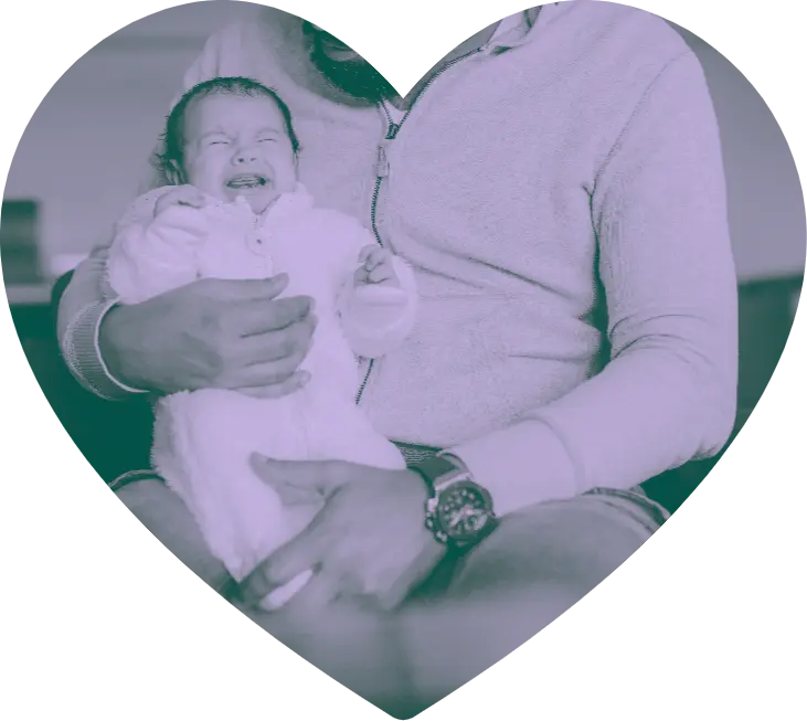 An infant crying while being held.