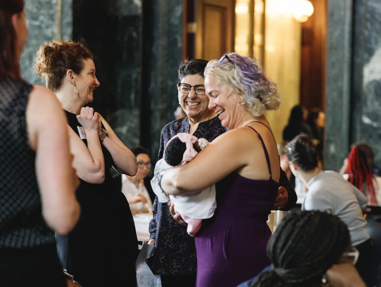 Family Connects event, woman holding a baby and smiling with two other women