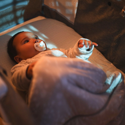 A baby on its back in a crib